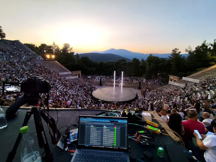 A laptop running the cues at Epidaurus, the orchestra in front.