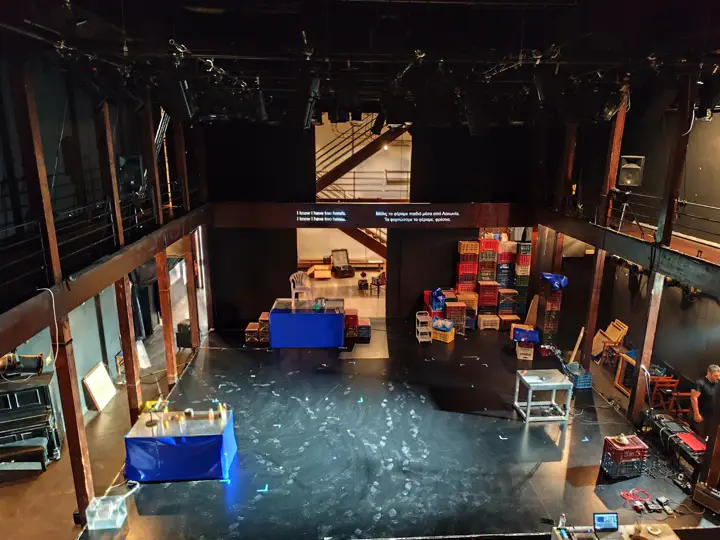 A rehearsal, titles on a screen above the floor.